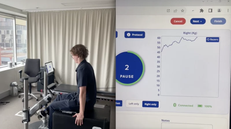 Patient cycling on a rehabilitation ergometer beside a screen showing live performance data