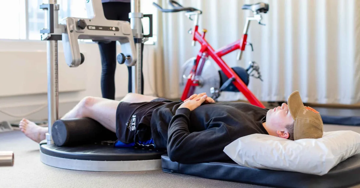 Athlete lying on a KangaTech rig for lower-limb strength testing at Saunders Physiotherapy